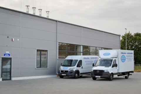 Samochody dostawcze Pralni Perfekt przed siedzibą firmy, gotowe do transportu bielizny